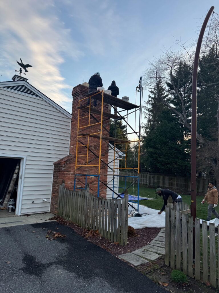 Removed the old brick chimney, built a new concrete-block chimney with brick exterior, and added a stone fireplace face with integrated mantle supports.