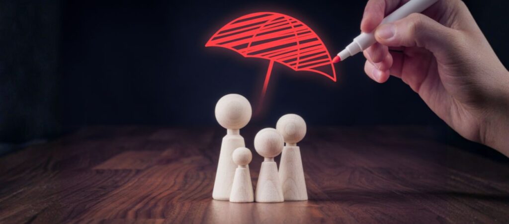 A hand drawing a red umbrella over a group of wooden figures, representing family protection and the importance of verifying roofing contractor insurance.